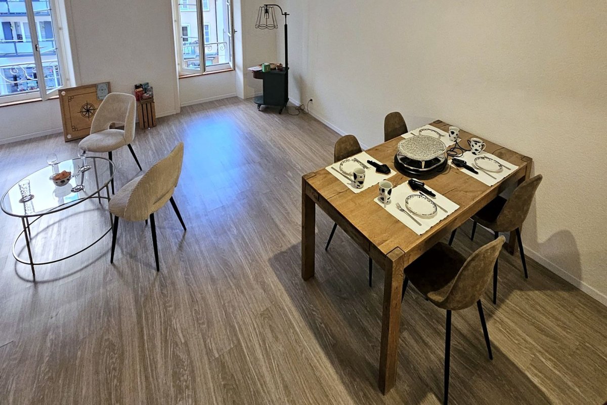 Salon lumineux du Repaire avec table en bois et grandes fenêtres