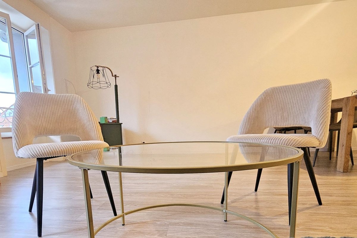 Salon avec deux fauteuils blancs et table basse en verre